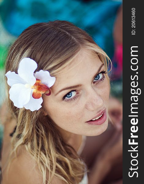 Portrait of beautiful young girl with blue eyes on the beach with beautiful flower in hair. Portrait of beautiful young girl with blue eyes on the beach with beautiful flower in hair