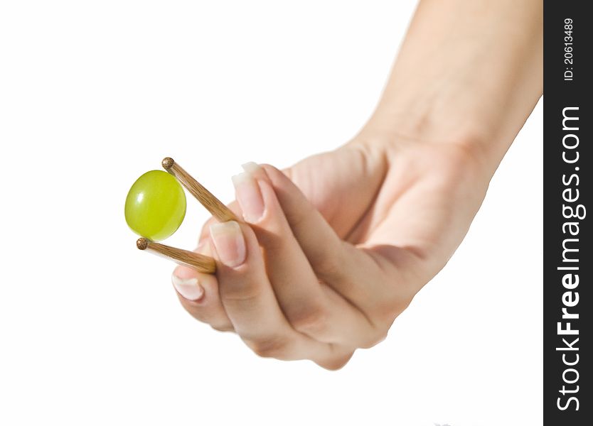 Green grape held with Chinese sticks by a beautiful woman hand. Green grape held with Chinese sticks by a beautiful woman hand.