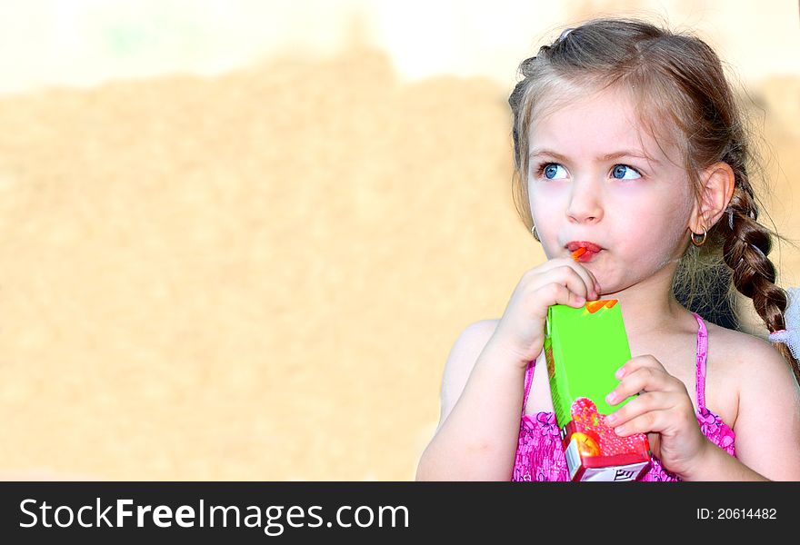 A little girl with blue eyes drinking juice outdoor. A little girl with blue eyes drinking juice outdoor