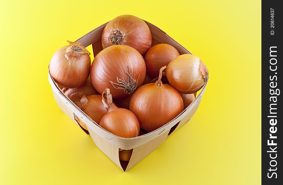 Onions In Box On Yellow Background.