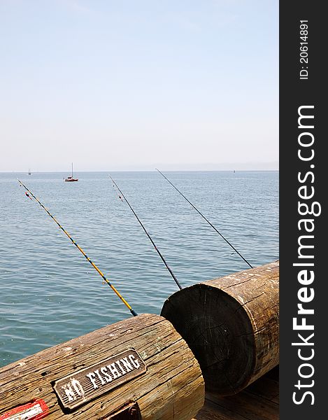 A view of fishing poles on Santa Barbara Pier, California. Contrasting image against a no fishing sign.