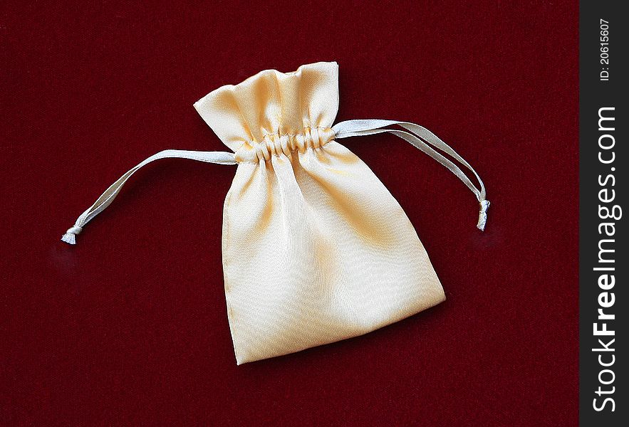 Beautiful Gold / Yellow Silk Pouch Bag for delicate items isolated on burgundy background