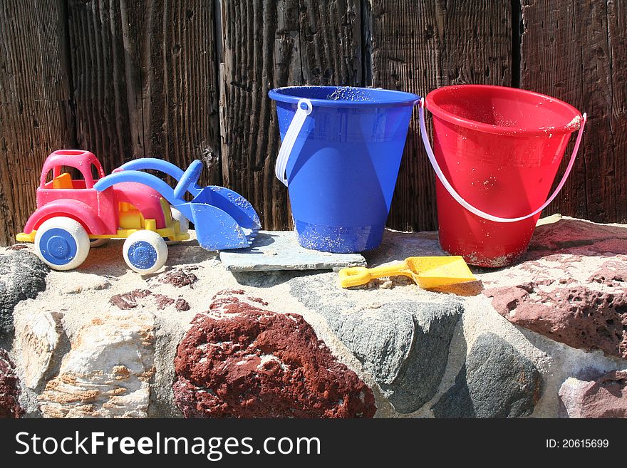 Beach buckets and a toy tractor line dup on a a wall. Beach buckets and a toy tractor line dup on a a wall.