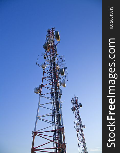 Communication towers on top of hill with blue sky background