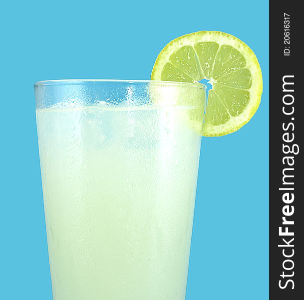 Ice cold glass of freshly squeezed lemonade with a slice of lemon isolated on an aqua cyan background.