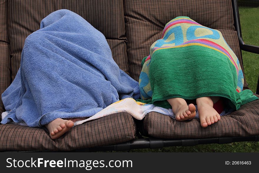 Two kids on a chair hidding with towels. Two kids on a chair hidding with towels