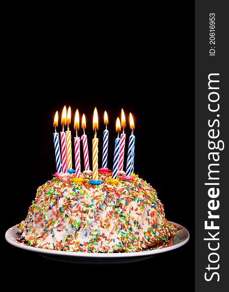 A cake with many coloured candles before black background. A cake with many coloured candles before black background