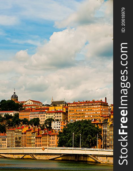 A bright day in the city of Lyon the colourful stone buildings sit near the bridge under big white clouds one day in summer. A bright day in the city of Lyon the colourful stone buildings sit near the bridge under big white clouds one day in summer.