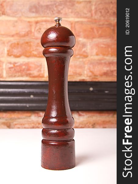 Pepper wooden grinder with brick wall in the background. Pepper wooden grinder with brick wall in the background