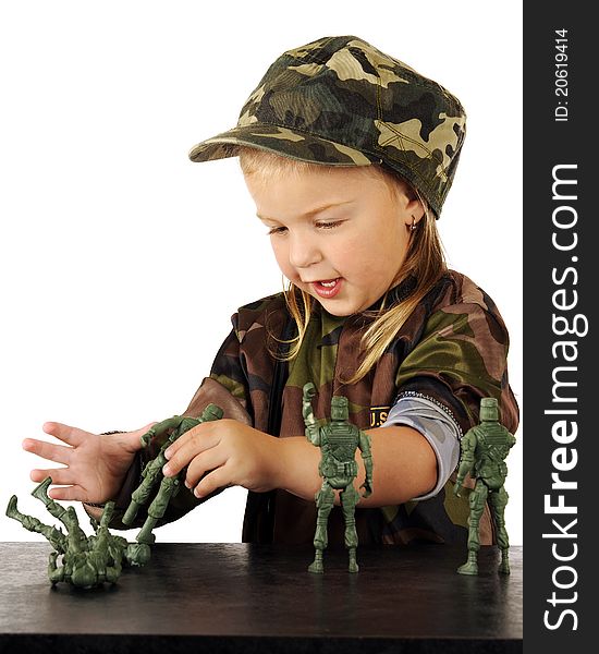 A cute preschooler in army garb playing with toy soldiers on a counter top. A cute preschooler in army garb playing with toy soldiers on a counter top.