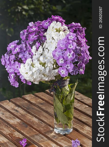 Bouquet of pink and white phloxes on a wooden little table in a garden. Bouquet of pink and white phloxes on a wooden little table in a garden