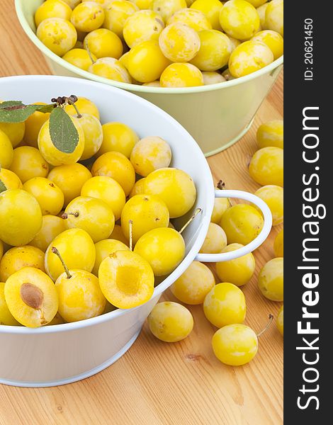 Studio-shot of small yellow plums also known as mellow mirabelles, on a wooden countertop.