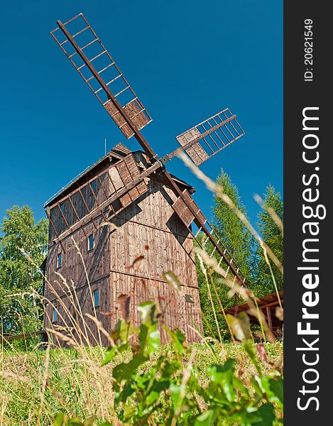 Old traditional wooden windmill hidden in forest.