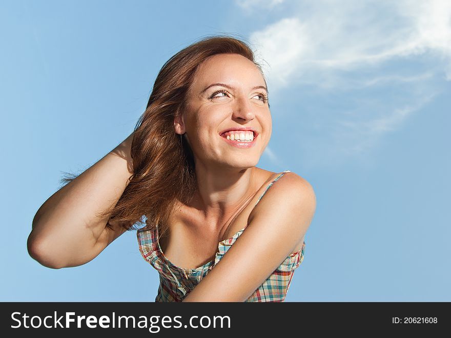 Beautiful young woman smiling against the sky