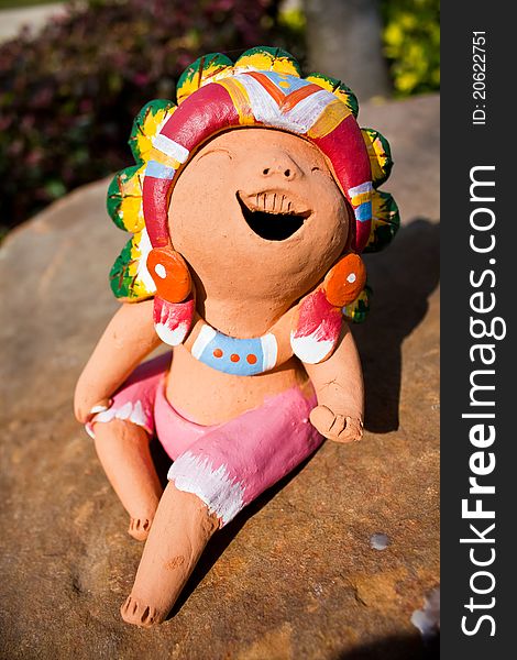 The Ceramic Laugh Doll sit on the Rock