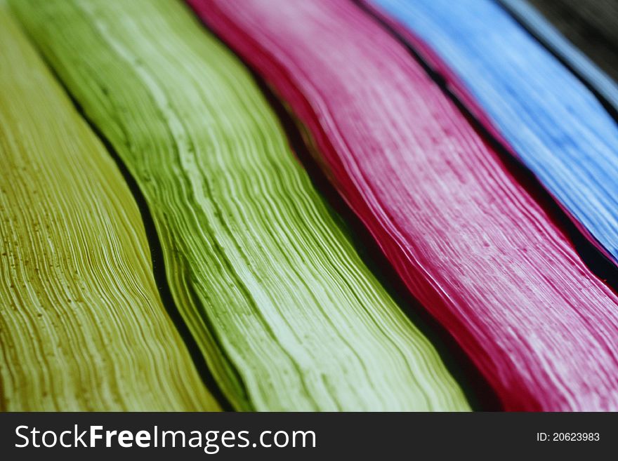 Colored paint streaks on glass with light shining from behind.