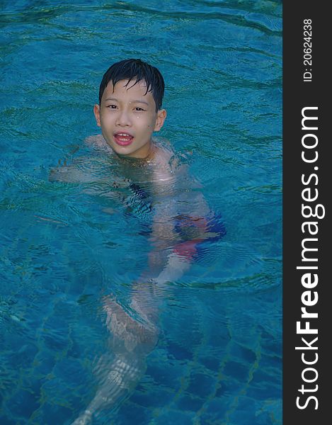 A happy child to swim in the blue water of the pool by a hot summer day. A happy child to swim in the blue water of the pool by a hot summer day
