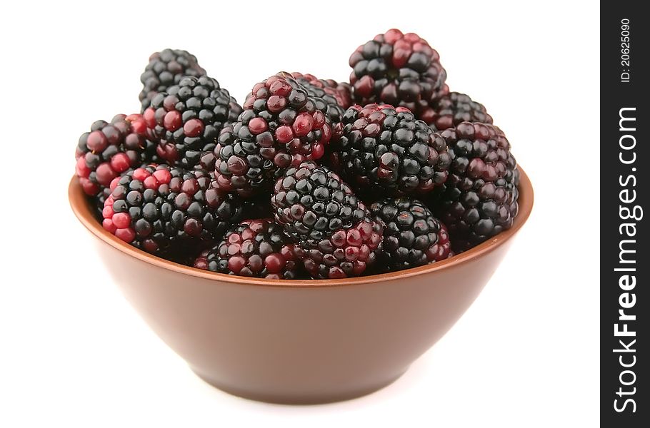 Ripe blackberry in a plate on a white background