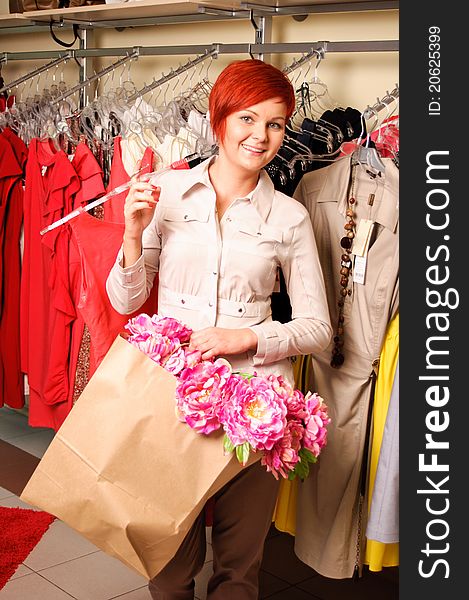 Beautiful caucasian woman holding a dress smiling at the camera. Beautiful caucasian woman holding a dress smiling at the camera