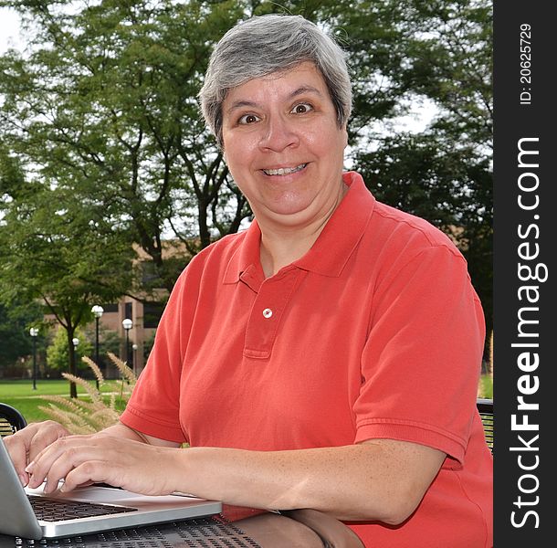 Happy middle-aged woman at table with laptop. Happy middle-aged woman at table with laptop