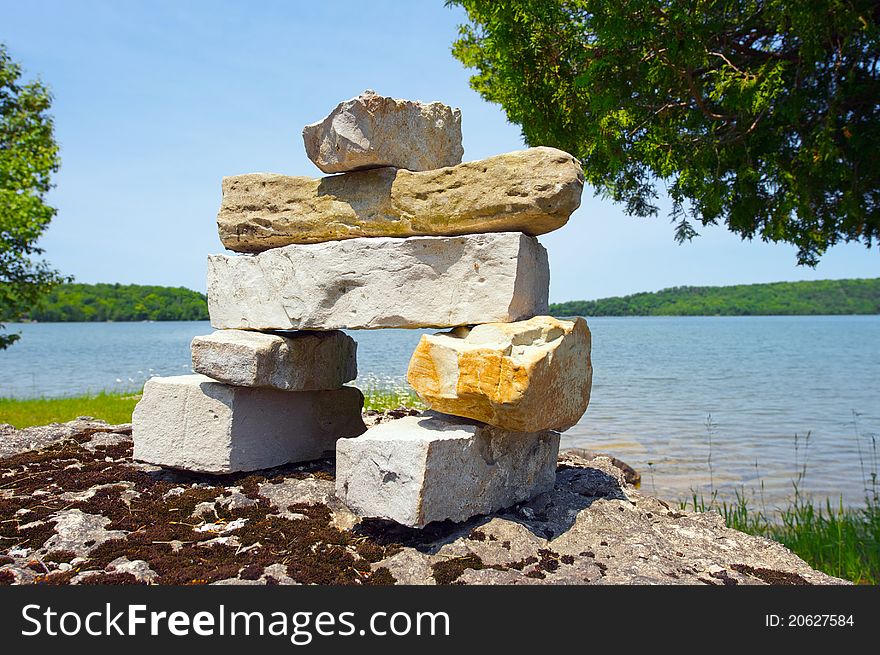 Wide angle image of an inukshuk overlooking a lake in Canada in the summer. Wide angle image of an inukshuk overlooking a lake in Canada in the summer.