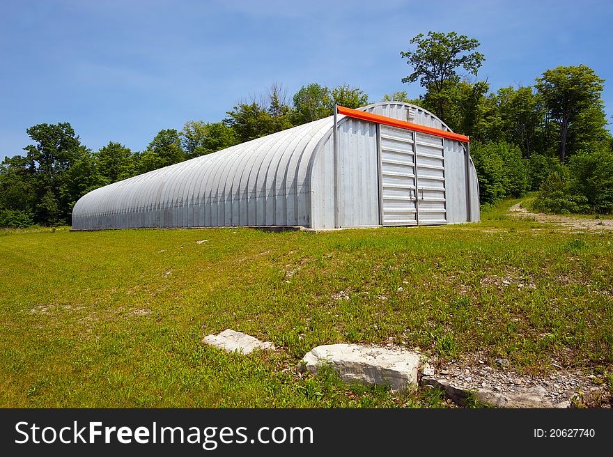 Wide angle image of a huge steel warehouse on the edge of a forest. Wide angle image of a huge steel warehouse on the edge of a forest.