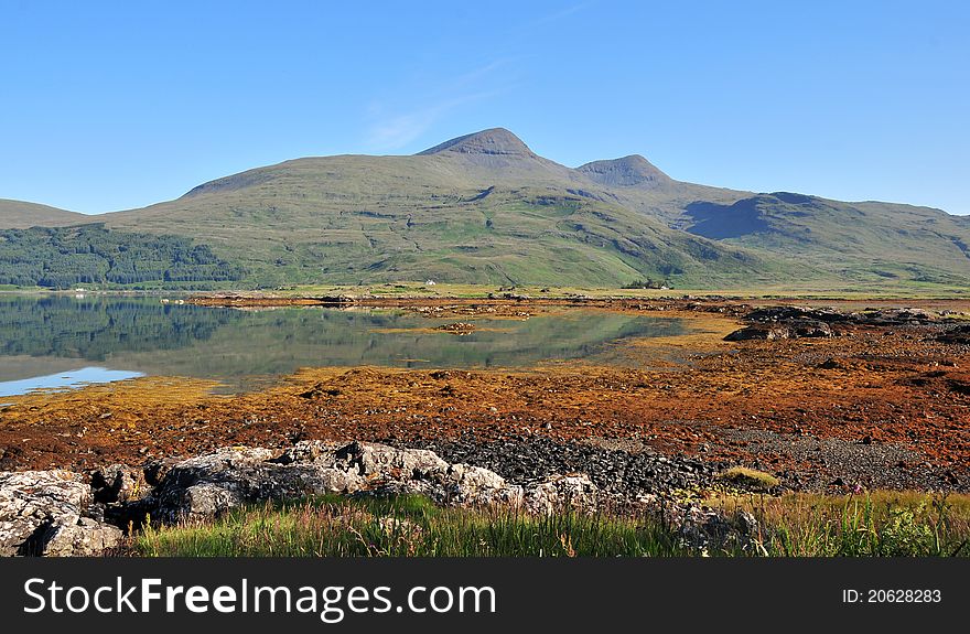 Loch Beg, Isles of  Mull, Argyll and Bute, Scotland, U.K. on the A879  Loch Scridain is a 15-kilometre-long &#x28;9-mile&#x29; sea loch, with a west-southwest aspect, on the western, or Atlantic coastline of the Isle of Mull, in the Inner Hebrides, Argyll and Bute, Scotland. Loch Scridain extends inland as far as the island&#x27;s only Munro and extinct volcano, Ben More, a large massif on the Ardmeanach peninsula to the north; the imposing Bearraich hill overlooks the mouth of the loch. To the south is the Ross of Mull, the longest peninsula on Mull, that reaches past the sea loch boundary into the Atlantic. Near the head of Loch Scridain is the Aird of Kinloch, a small peninsula that almost separates the main loch from the small inner sea loch, Loch Beg. Loch Beg is fed by the River Coladoir. Seabank Villa on the lochside at Kilfinichen Bay is the type locality for the mineral mullite. Loch Scridain has three settlements, Tiroran, Kilfinichen, and Pennyghael, with a total population of about 60. The A849 to Bunessan and Fionnphort runs along the southern shore of the loch and there is a turn off in Pennyghael to Carsaig Bay. Loch Scridain to the Ardmeanach peninsula is a lava landscape in which the lava flows have created a layered effect. Basalt lava is rich in minerals and the land between the crags is green and fertile. There is black basalt, stained orange in places. The orange colour represents the top surfaces of the flow, weathered by the tropical climate of 60