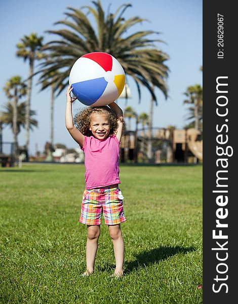 Litle girl playing at the park with a beach ball