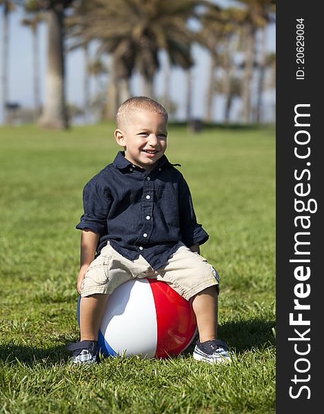 Little boy sitting on a beach ball at the park. Little boy sitting on a beach ball at the park