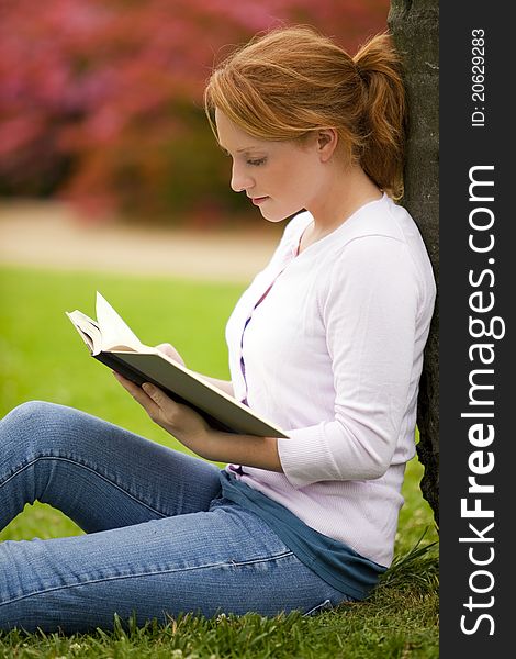Young woman sitting outside reading. Young woman sitting outside reading