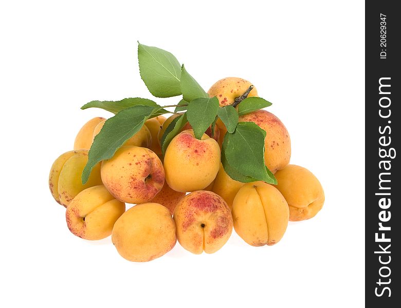 Apricots with the branch of leaves lie a heap on a white background