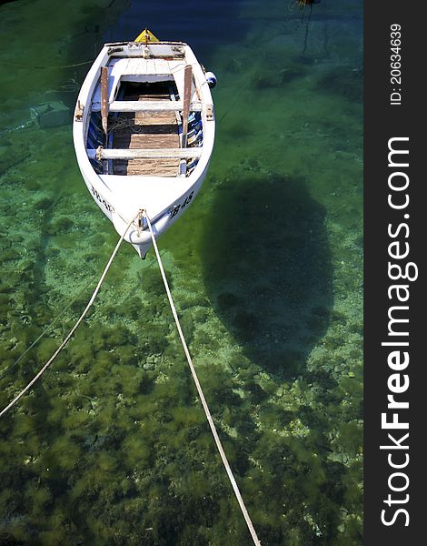 White berthed fishing boat on the emerald sea with the reflection on the seabed. White berthed fishing boat on the emerald sea with the reflection on the seabed