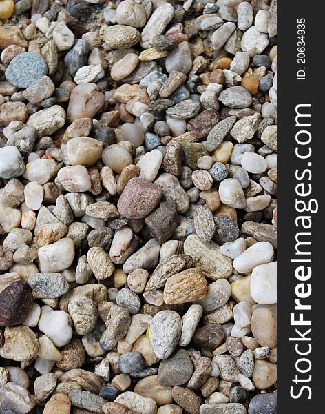 A close up view of smooth polished multicolored stones  washed ashore on the beach.