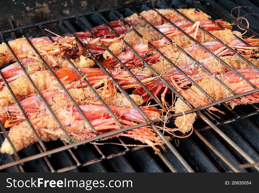 King prawns coated with breadcrumbs while cooking on a barbecue grill. King prawns coated with breadcrumbs while cooking on a barbecue grill