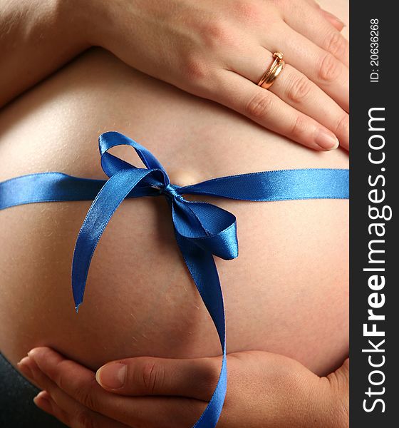 Pregnant woman with a blue bow on her belly. Pregnant woman with a blue bow on her belly