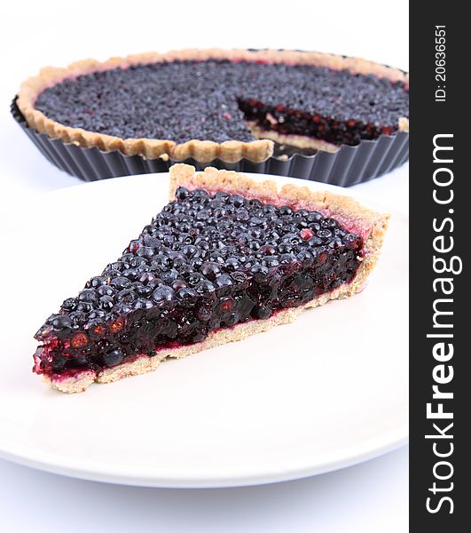 Blueberry Tart: a portion on a plate and in a tart pan on a white background