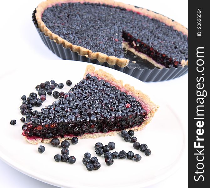 Blueberry Tart: a portion on a plate and in a tart pan on a white background