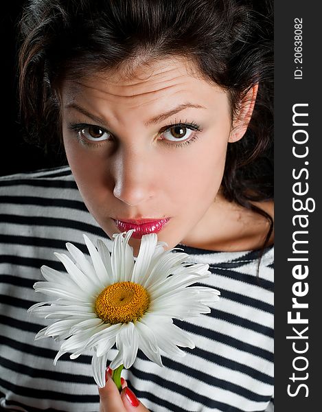 Beautiful young woman with chamomile in hand on black background