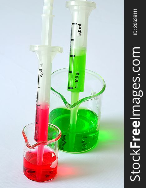 A two pipet in the beaker with red and green solution. A two pipet in the beaker with red and green solution