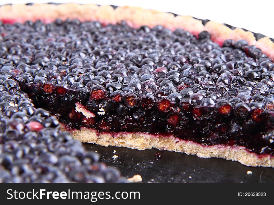 Blueberry Tart in a tart pan, with a slice cut out, on a white background