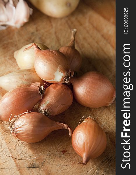 Baby onions grouped together on a chopping board, ready for preparation to cook.