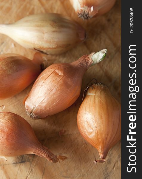 Baby onions grouped together on a chopping board, ready for preparation to cook.