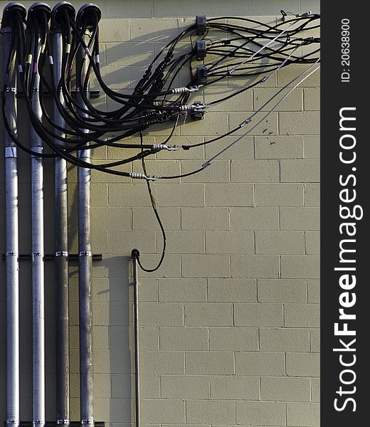 A group of wiring against a building secured for neatness in tubes and connectors. A group of wiring against a building secured for neatness in tubes and connectors.