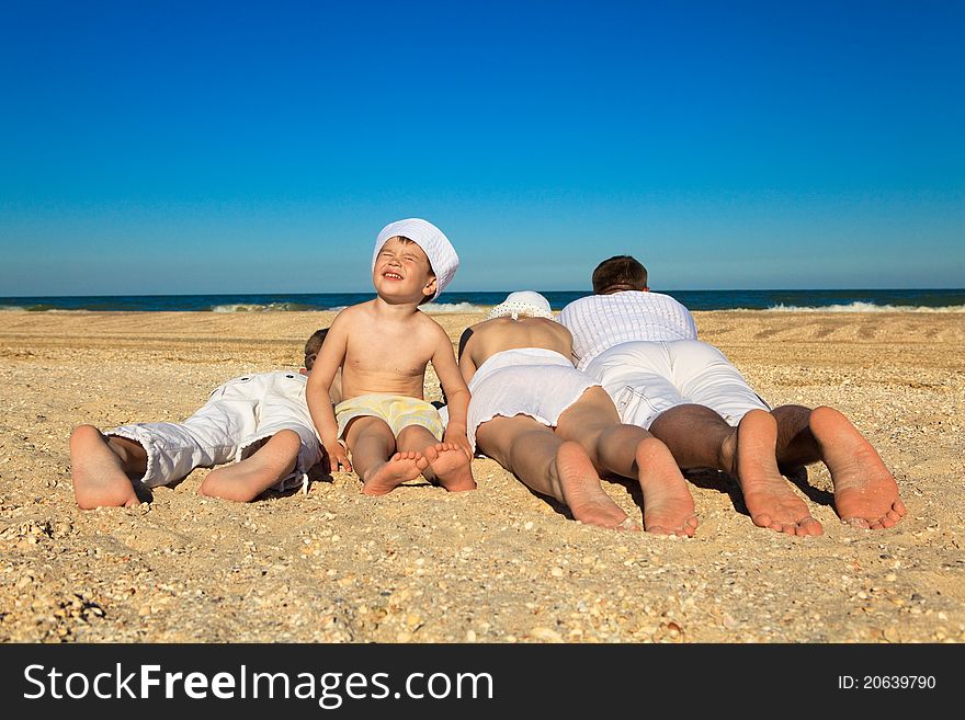 Photo of family lying on sand on background of blue sky