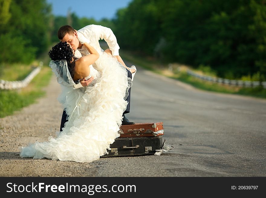 Young newlywed couple kissing on a road.