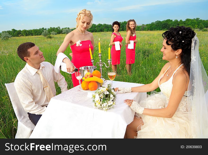 Bride and groom sitting at wedding table on the field