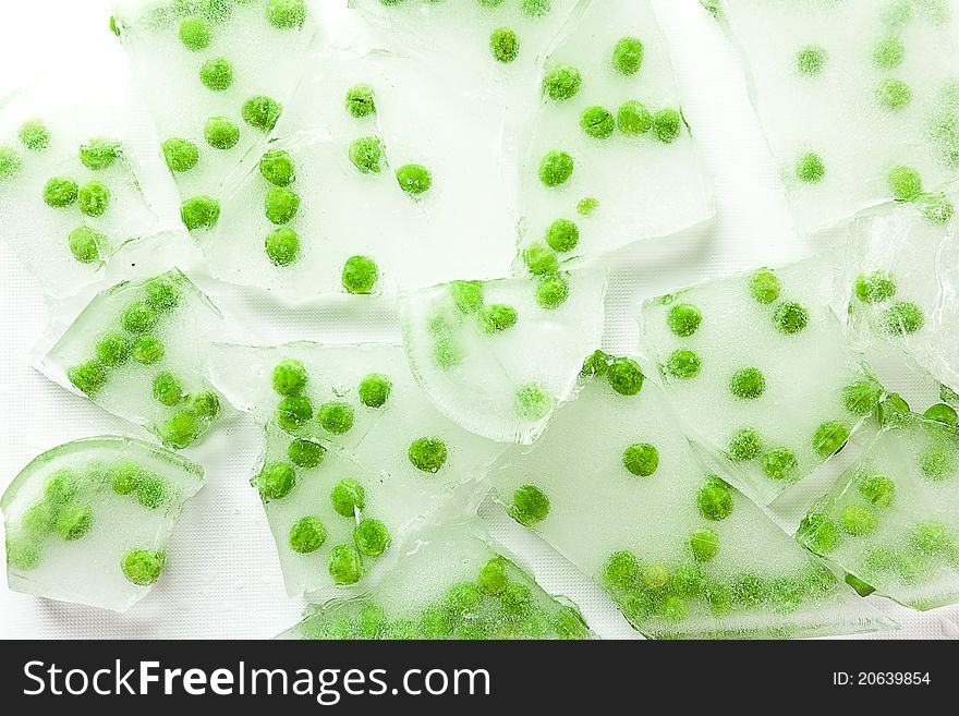 Green peas frozen in cracked and broken pieces of thick ice. Green peas frozen in cracked and broken pieces of thick ice