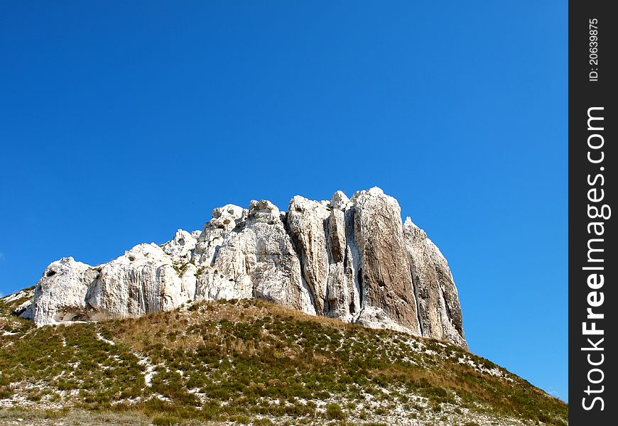 Photo of cretaceous rocky formation against the blue sky with clouds