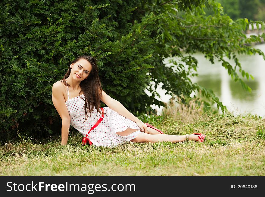 Beautiful attractive woman sitting on a green grass. Smiles. Beautiful attractive woman sitting on a green grass. Smiles.