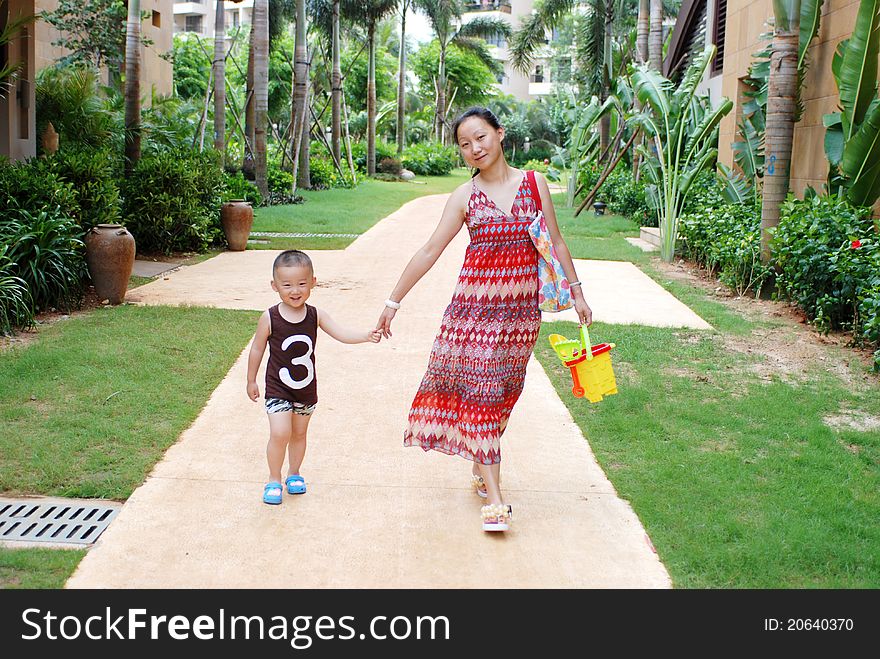 Asian young mother and son walk in tropical park. Asian young mother and son walk in tropical park